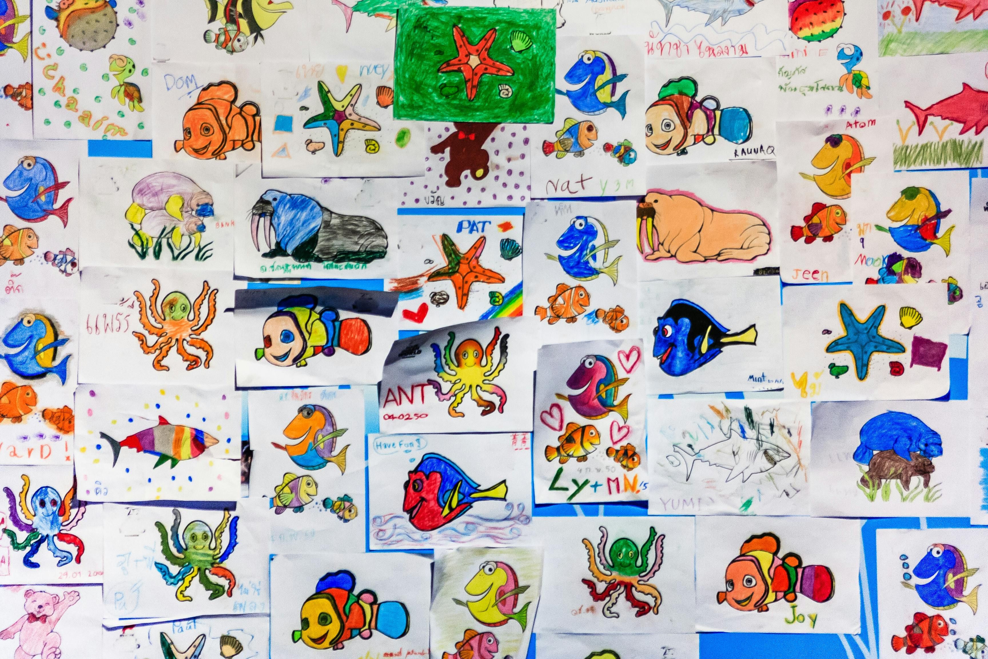 A wall of children's art with a rainbow of colors and a variety of textures.